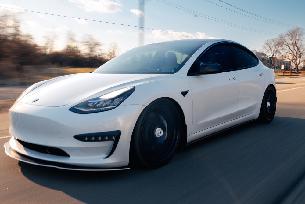 Adas Calibration, Tesla Repair, Hybrid/EV Repair In Merriam, KS At Done With Care Auto Repair. Tesla Model 3 driving on a road in Merriam, KS