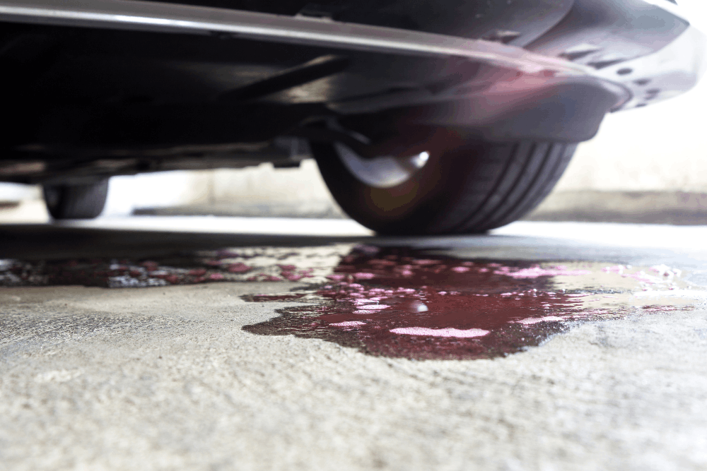 Coolant leak, auto repair in Merriam, KS, at Done With Care Auto Repair. Image of fluid pooled beneath a parked vehicle, highlighting the need for prompt diagnosis to help prevent further damage and maintain reliability.