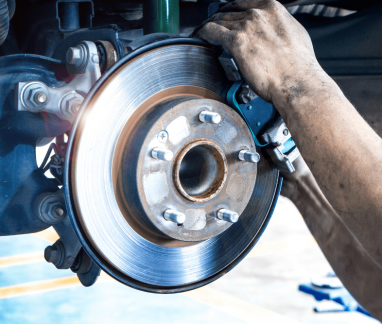 factory-scheduled maintenance, auto repair in Merriam, KS at Done With Care Auto Repair. An image of a mechanic working on the vehicle's brake system.